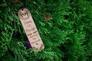 bookmark: crest on top, followed by text "Casey and Django Starting New Adventures" with engraved leaves.