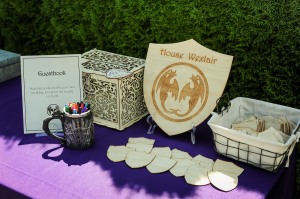 wooden shield engraved with crest and "House Wexlair"; smaller blank versions of same sit in front with instructions to decorate them for the guestbook.